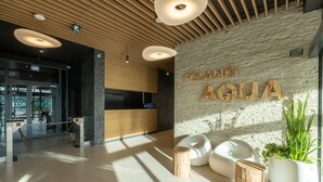 Un área de recepción con pared de piedra, techo de madera y un letrero que dice 'POLANKI AQUA'.