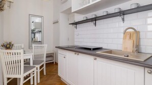 Cocina moderna con muebles blancos, encimera oscura y repisa colgante con tazas.