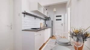 Cocina compacta con armarios blancos, encimera negra y repisa colgante.