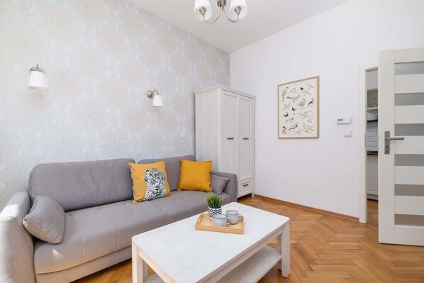 Ein modernes Wohnzimmer mit einem grauen Sofa, einem Holztisch und einer weißen Kommode.