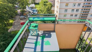 Un balcón con una mesa, sillas y barandilla verde.