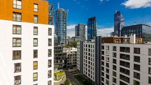 Un ensemble immobilier urbain moderne composé de plusieurs immeubles de grande hauteur, caractérisé par un mélange de façades en verre et en béton, et surplombé d’un ciel bleu clair.