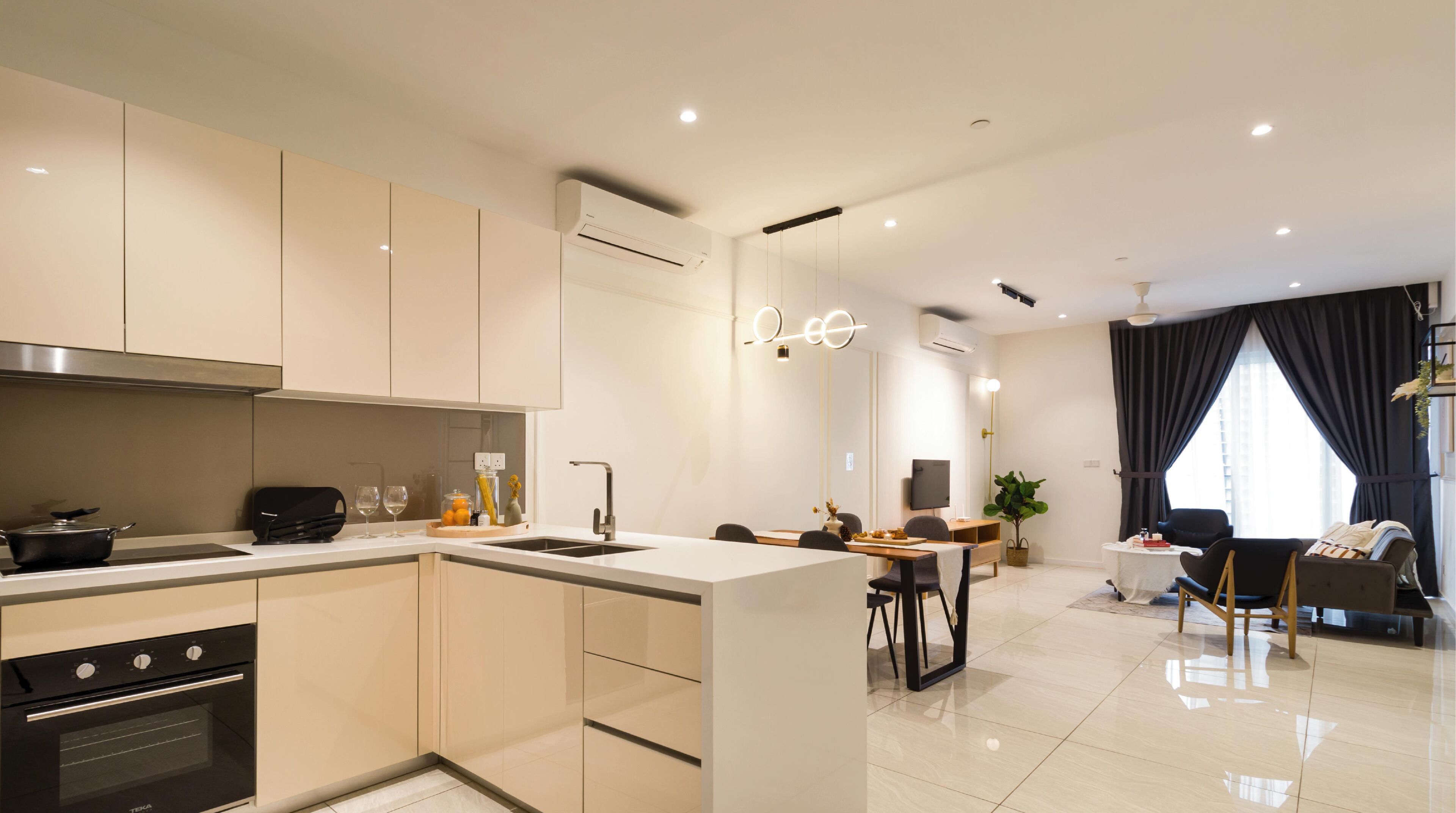 Een moderne keuken met een centraal eiland, een eethoek met een tafel en stoelen, en een zithoek met een bank en televisie.