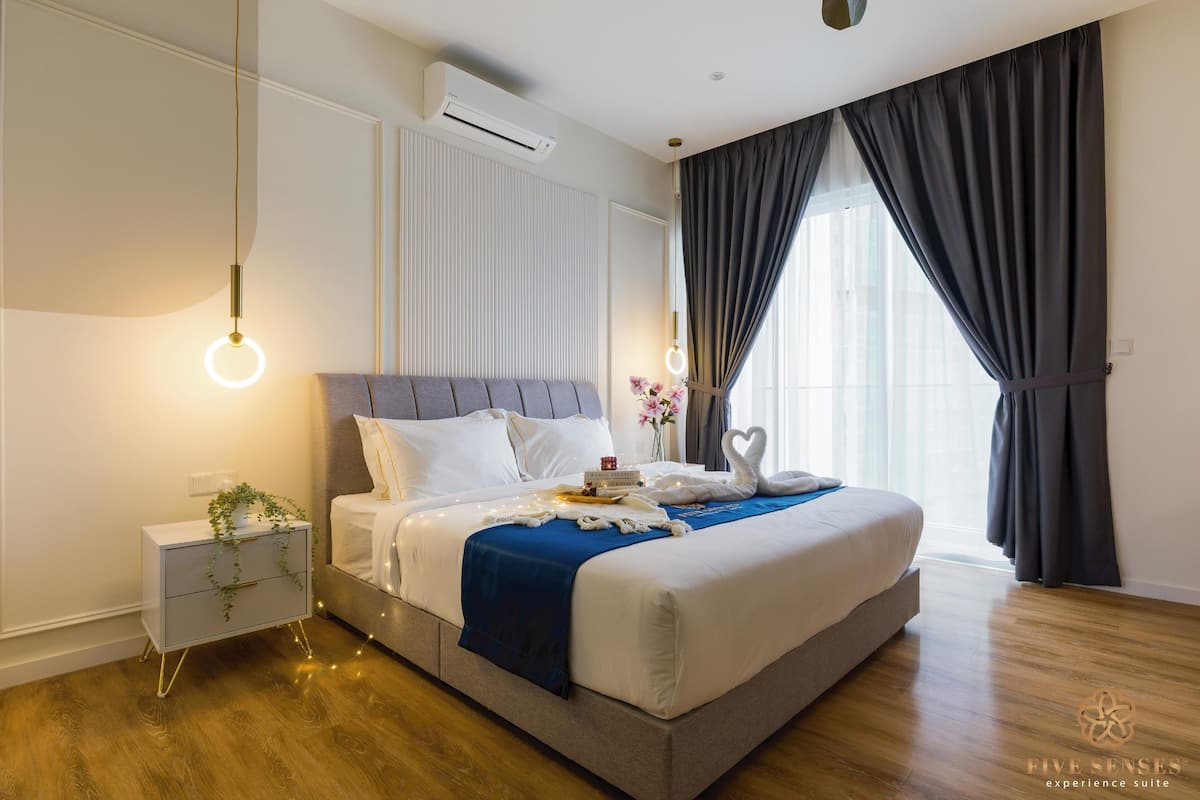 Een moderne slaapkamer met een groot bed, nachtkastjes, een airconditioning en uitzicht door dunne gordijnen.