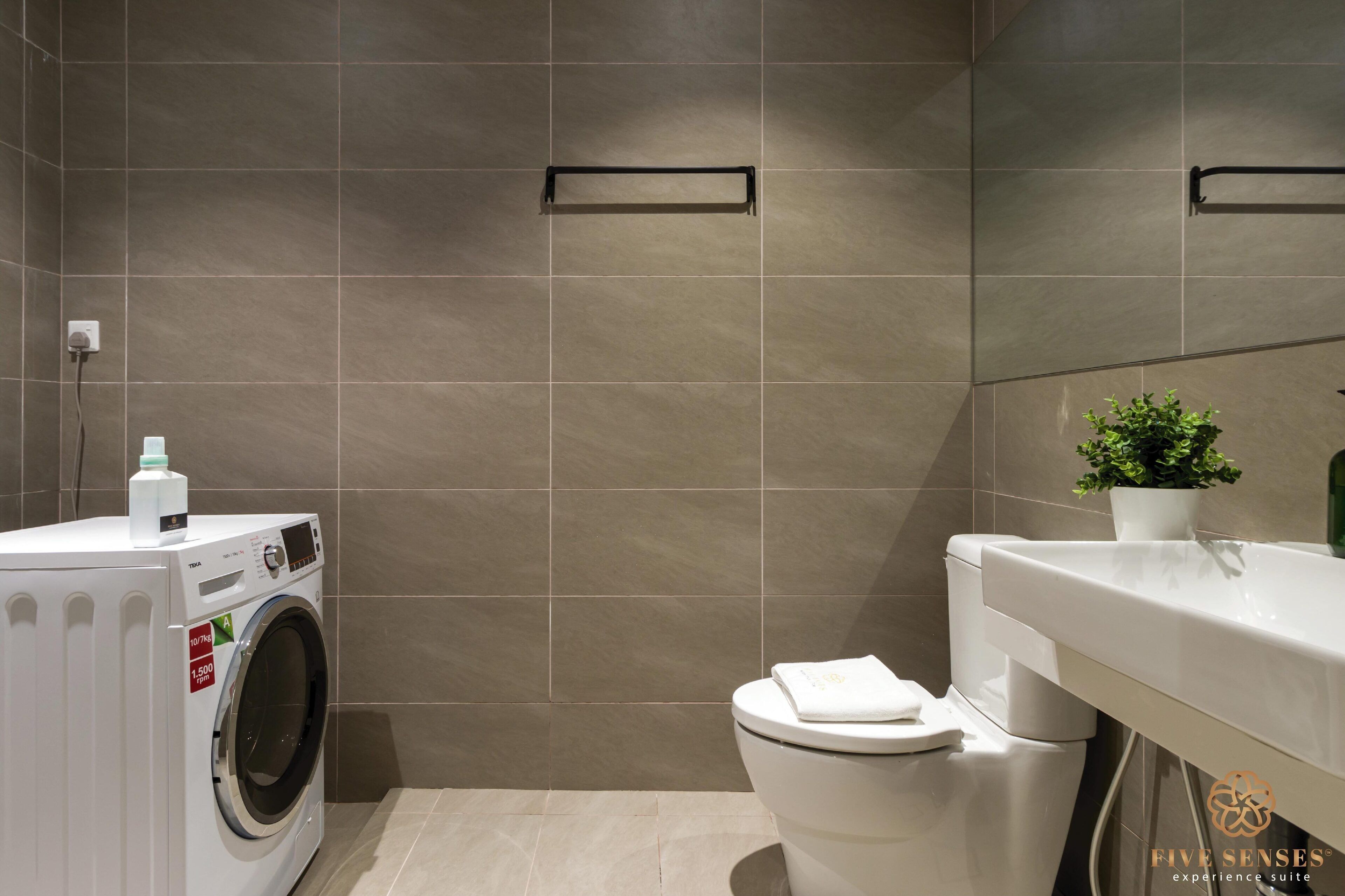 Un bagno moderno con lavatrice, vaso da bagno e una pianta in vaso.