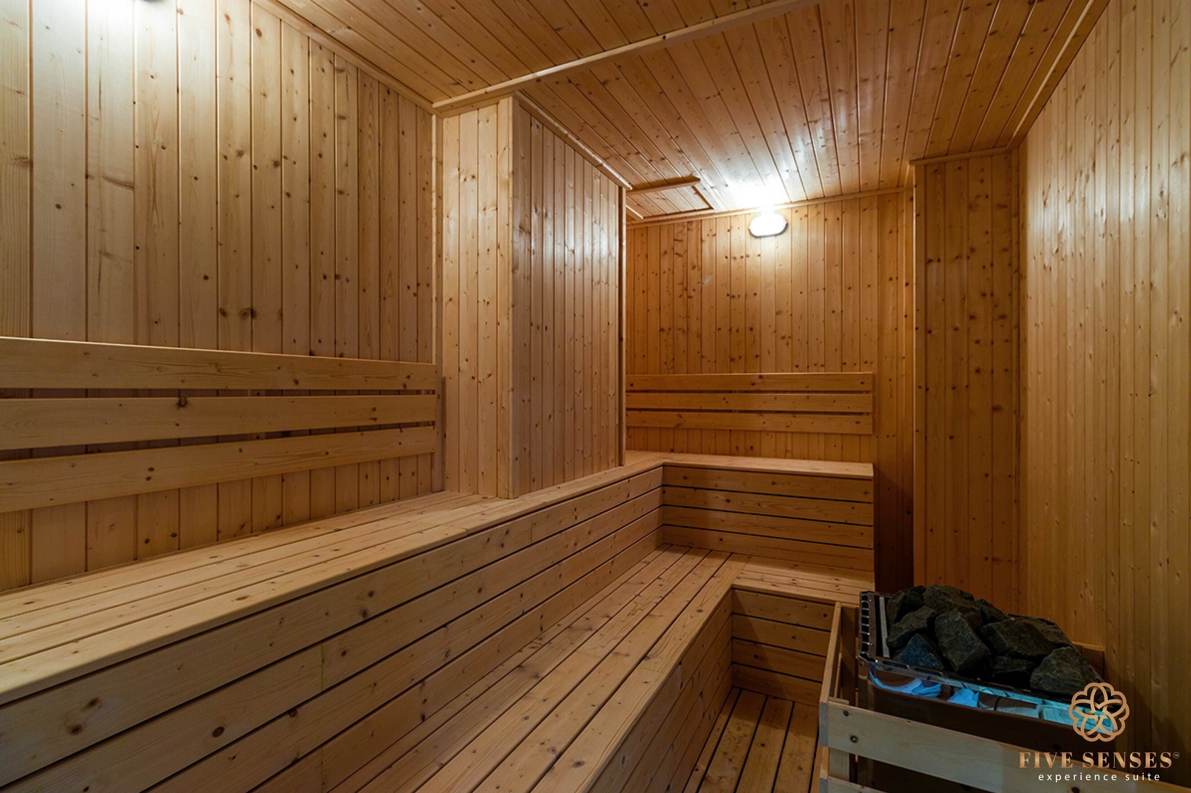 Uma sauna de madeira com bancos e uma bancada com uma bandeja de pedras.