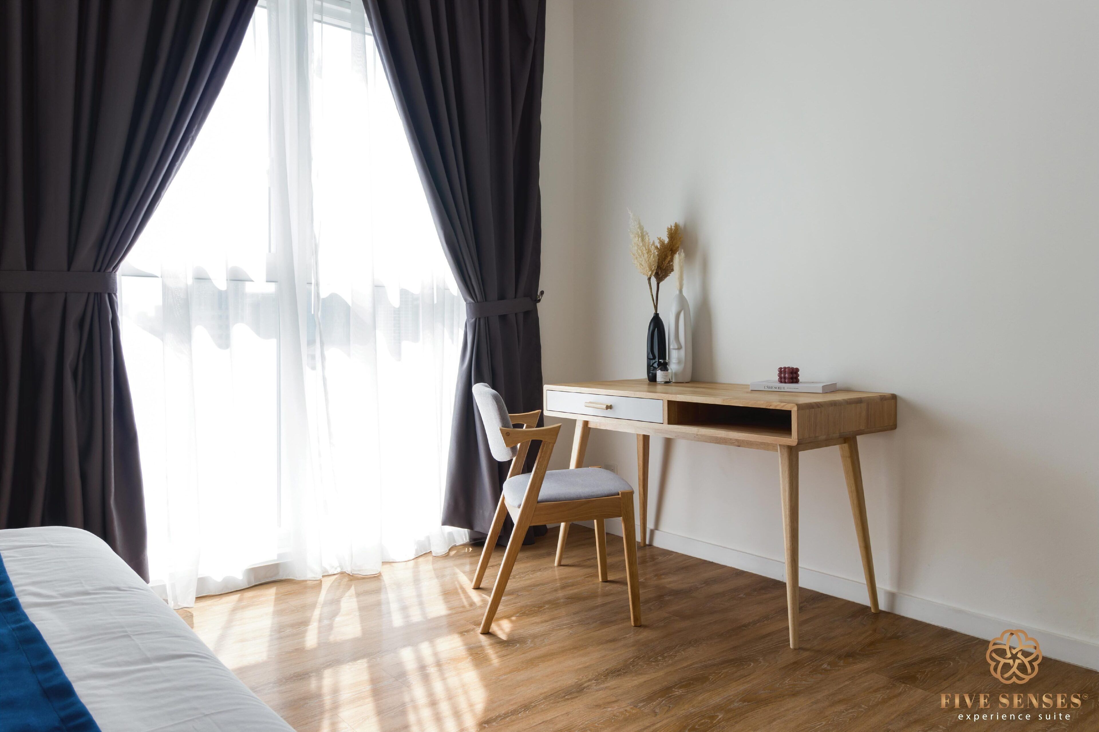 A bedroom with a bed, a desk with a chair, and a window with curtains.