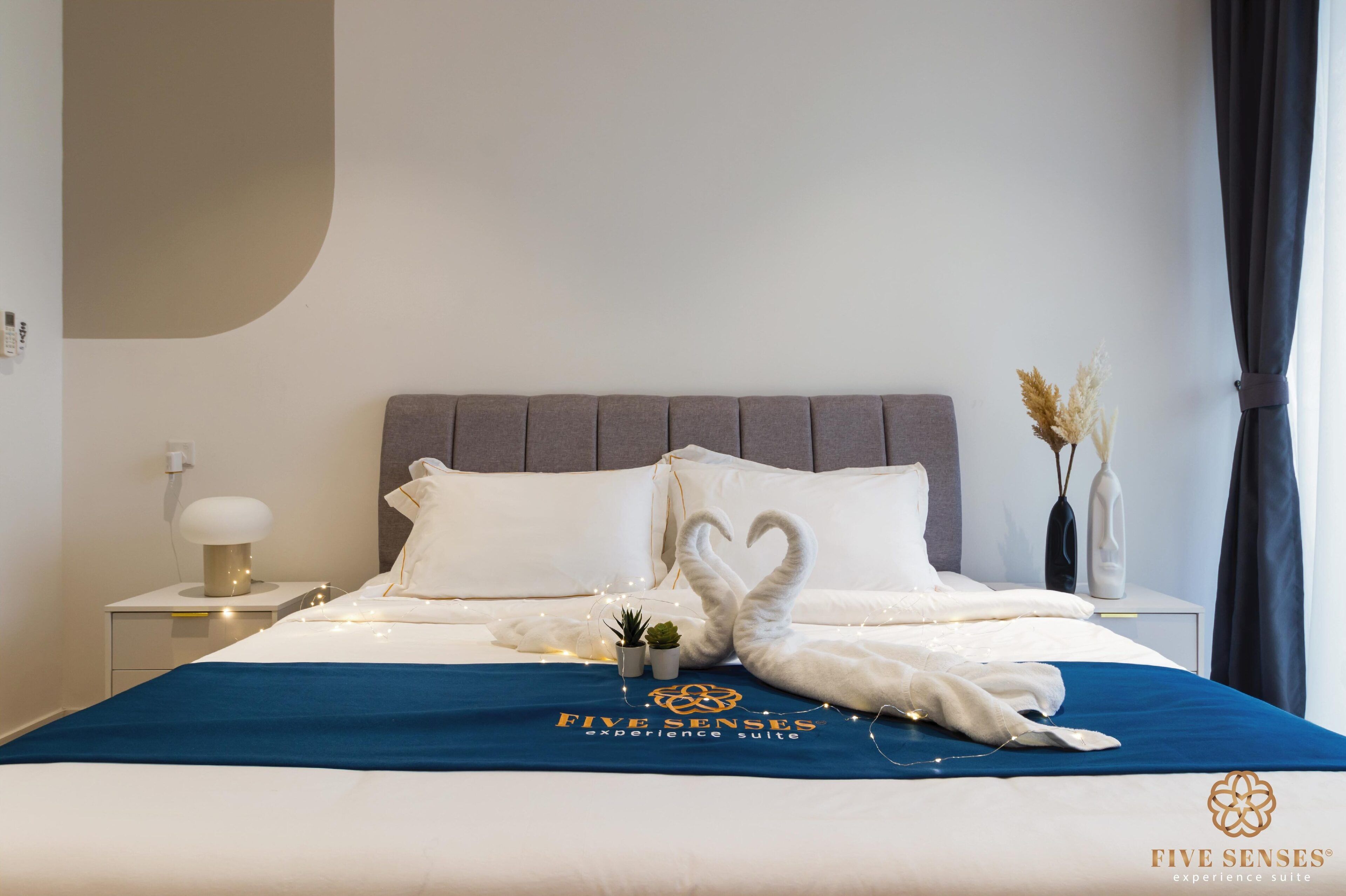 Ein ordentlich gemachtes Bett mit blauer Bettdecke, weißen Kissen und dekorativen Schwanenkissen.