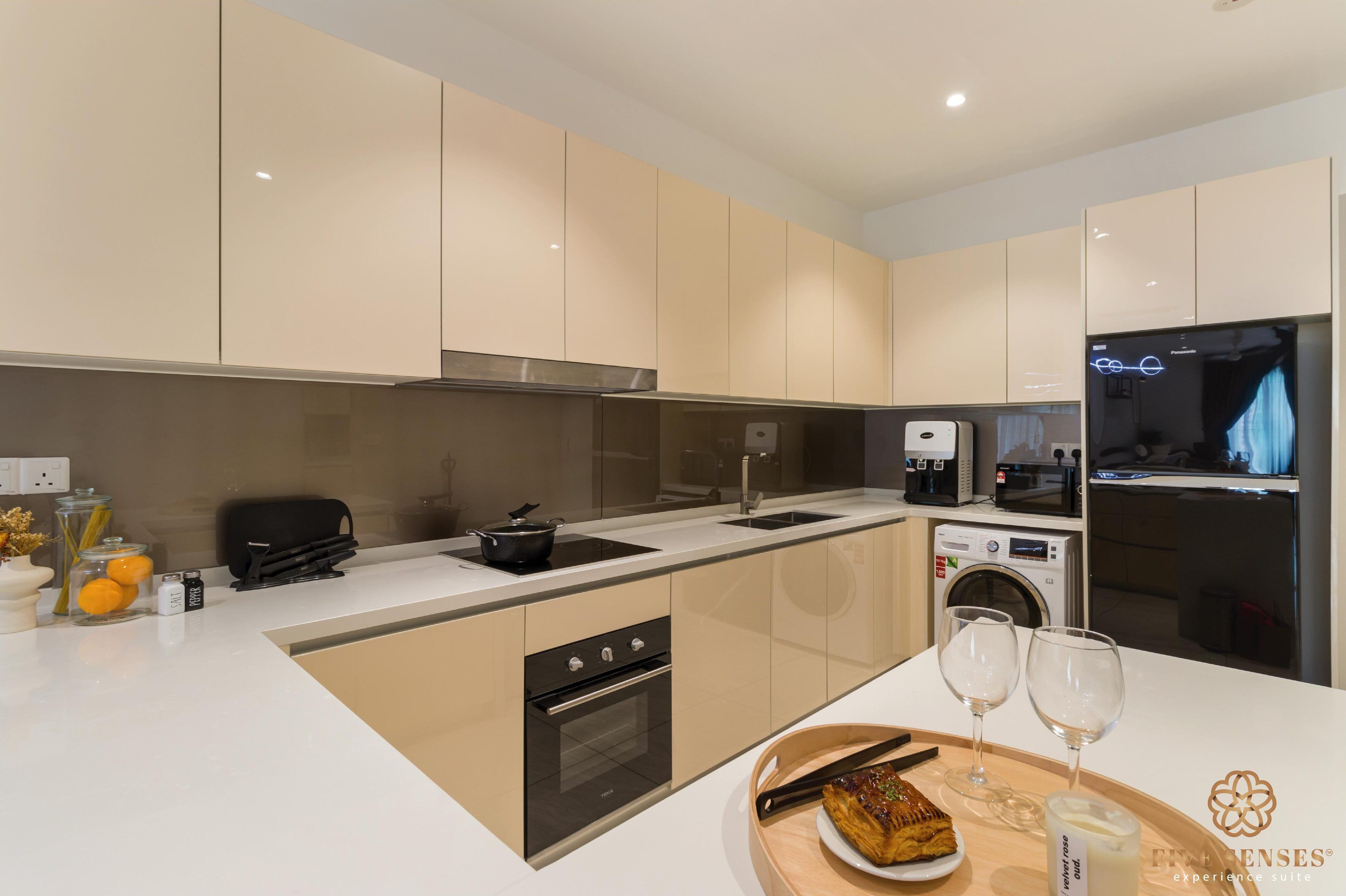 A modern kitchen with a central island, built-in oven, microwave, and washing machine.