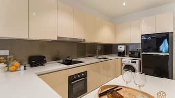 A modern kitchen with a central island, built-in oven, microwave, and washing machine.