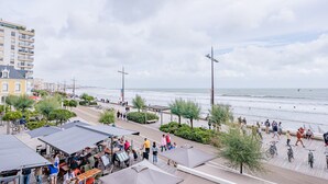 Eine Küstenpromenade mit Außenplätzen, einem Radweg und Blick aufs Meer.