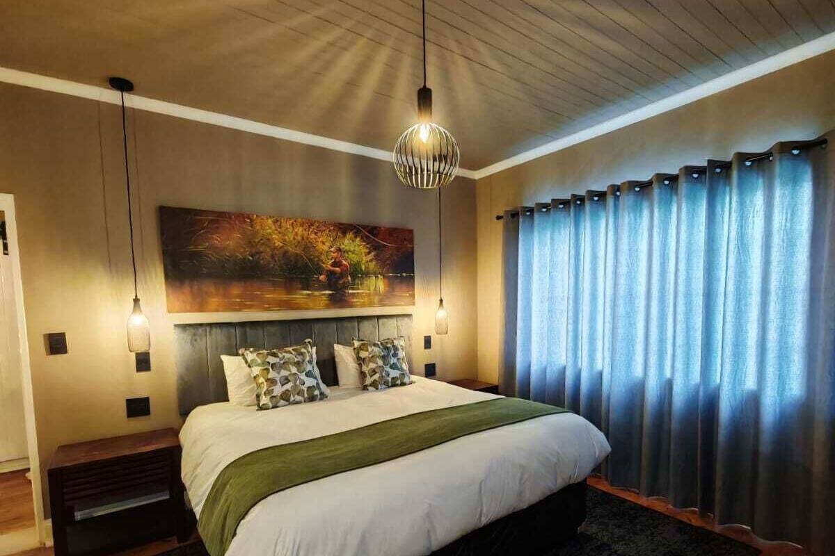 A bedroom with a large bed, a painting on the wall, and a window with curtains.