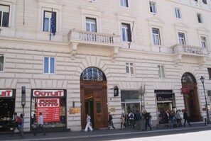 A building with multiple storefronts, including a visible sign for an outlet store and a hotel. - Monti 66 Hotel (Rome)