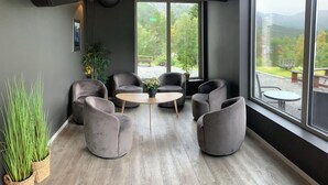 A modern meeting room with grey upholstered chairs, a round wooden table, and large windows offering a view of a park and mountains. - Kårdal Fjellstove (Voss)