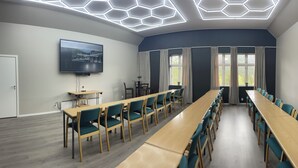 A conference room with a long table, chairs, a TV, and a modern ceiling design. - Kårdal Fjellstove (Voss)