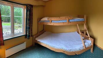 Sleep comfortably in this cozy room with a bunk bed featuring a lower and upper bunk, both with wooden frames.