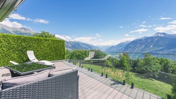 Un balcon avec vue sur les montagnes et un lac.