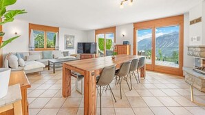 Un vaste espace de vie comprenant une table à manger en bois, des sièges confortables, un téléviseur et une cheminée.
