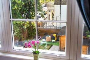 A window view of a backyard with a wooden deck, a small table, and a chair.