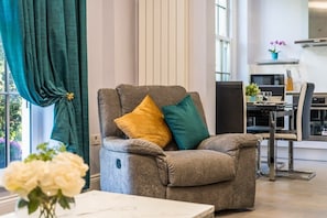 A modern living room with a grey sofa, a small table, and a window with curtains.