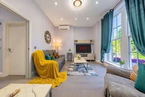 A modern living room with a sofa, a coffee table, and a TV.