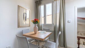 A dining area with a wooden table, four chairs, a vase with flowers, and a framed picture on the wall. - Salvemini Home in Firenze (Florence)