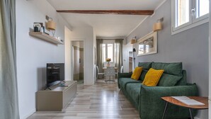 A modern living room with a green sofa, wooden flooring, and a TV on a stand. - Salvemini Home in Firenze (Florence)