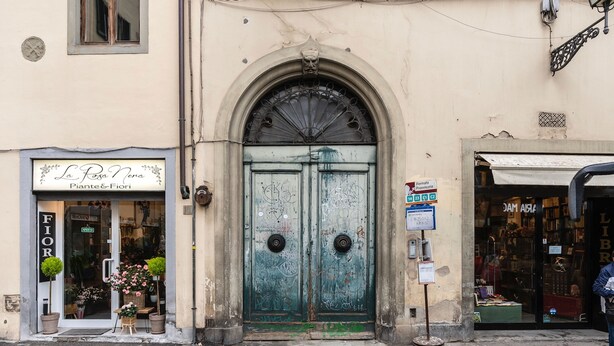 A storefront with a green door, a sign for 'La Rosa Nera' with flowers outside, and a 'Fiori' sign on the left. - Salvemini Home in Firenze (Florence)