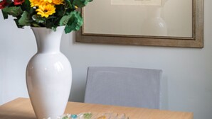 A framed artwork on a wall, a white vase with flowers, and a glass bowl on a table. - Salvemini Home in Firenze (Florence)