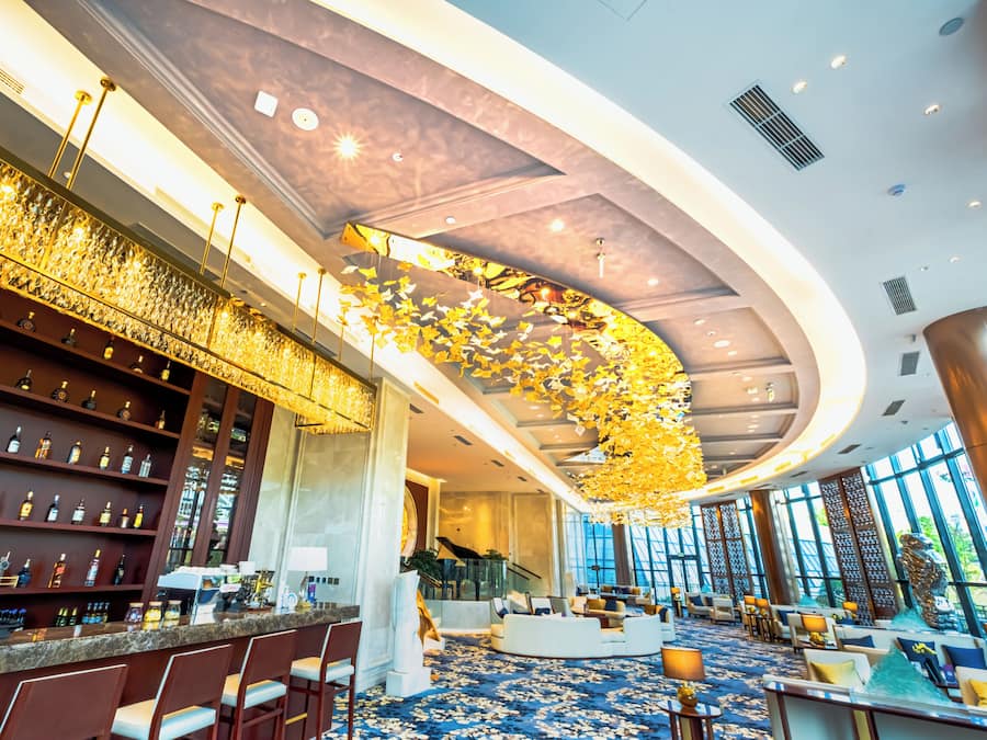Un hall d’hôtel moderne doté d’un bar, d’un espace salon et de grandes fenêtres.