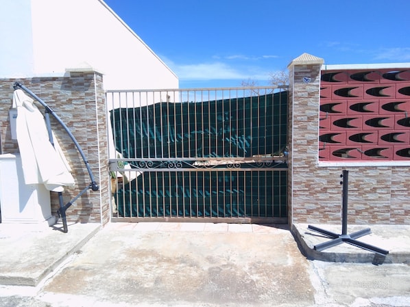 A gated entrance with a metal gate, a concrete pathway, and a brick wall.
