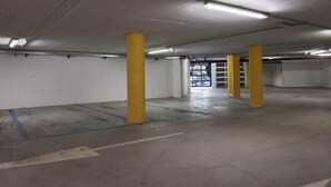 An empty parking garage with yellow pillars, concrete floors, and a visible exit door. - Acquaseria 310 in Ponte di Legno (Ponte di Legno)