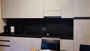 A modern kitchen with a black countertop, stainless steel appliances, and a dining area with a wooden table and chairs. - Acquaseria 310 in Ponte di Legno (Ponte di Legno)