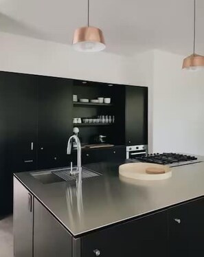 A modern kitchen with a central island, stainless steel appliances, and pendant lighting.