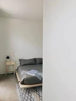 A bedroom with a bed, a bedside table, and a nightstand.