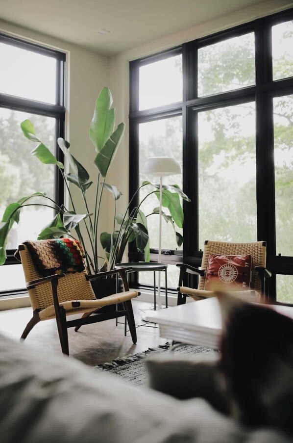 A room with large windows, a sofa, two chairs, and a table.