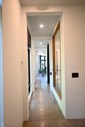 A hallway with a wooden floor, white walls, and a glass door on the right. - NorthShore, Modern Cabin 656 (Northport)