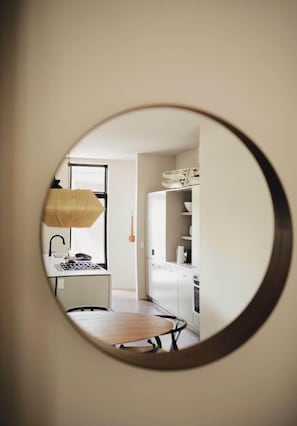 A circular view of a kitchen with a dining table, a hanging light fixture, and a window.
