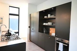 A modern kitchen with a gas stove, dark cabinetry, and a built-in oven.
