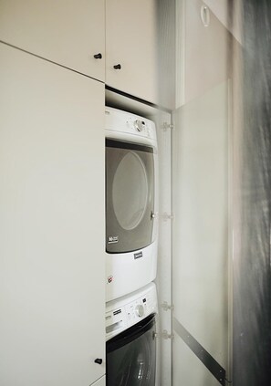 A compact, wall-mounted washer and dryer unit with a stainless steel finish, integrated into a white cabinetry structure. - NorthShore, Modern Cabin 656 (Northport)
