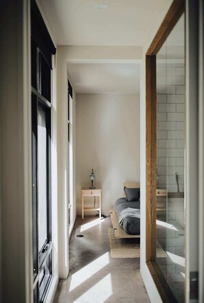 A narrow hallway leading to a bedroom with a bed, a nightstand, and a window. - NorthShore, Modern Cabin 656 (Northport)