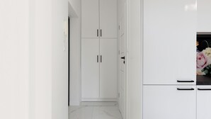 A modern kitchen with white cabinetry, a marble floor, and a vase of flowers on the counter. - Elite Apartments Sopot Seaside (Sopot)