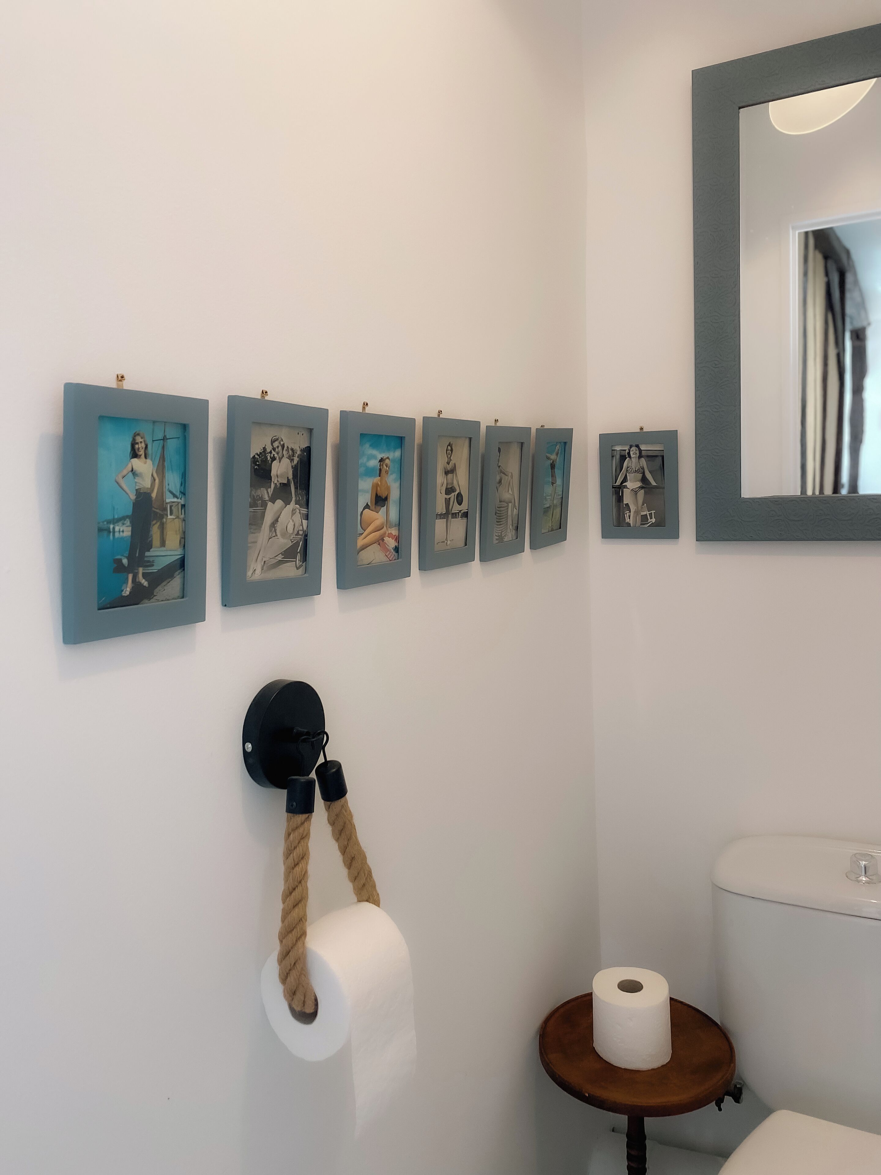 Een badkamer met een toilet, een wastafel en een spiegel. Er hangen zes ingelijste foto's aan de muur.