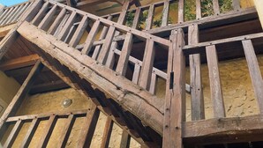 A wooden staircase with a view of the sky and a building with a green wall and plants.