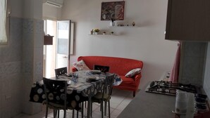 Una cocina compacta con una mesa de comedor para cuatro personas, un sofá rojo y una estufa a gas.