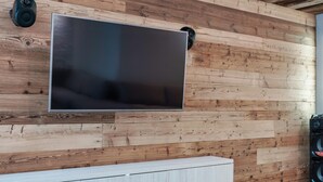 Ein modernes Wohnzimmer mit einem großen Flachbildfernseher an einer Holzwand.