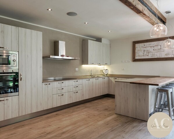 A modern kitchen with wooden cabinets, stainless steel appliances, and a wooden countertop. - La Tavolata in Incudine (Incudine)