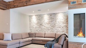 Ein modernes Wohnzimmer mit Steinwand, Holzboden und Kamin.