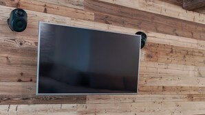 Un soggiorno moderno con un'ampia televisione a schermo piatto montata su una parete in legno.