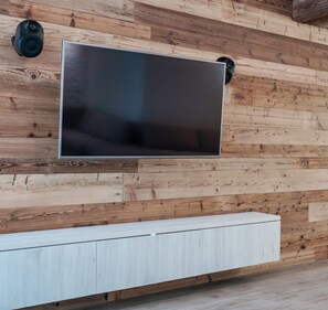 A modern living room with a large flat-screen TV mounted on a wooden wall.